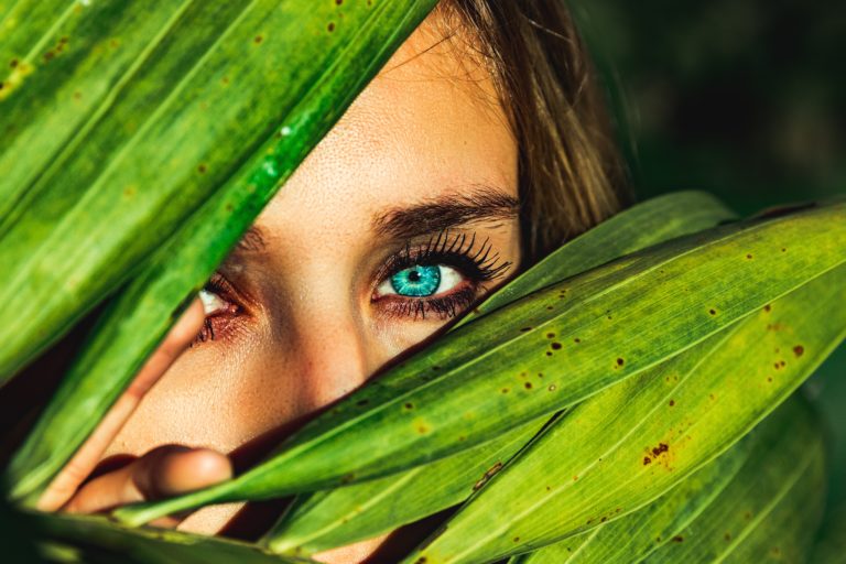 Girl behind a leafy tree hiding her face